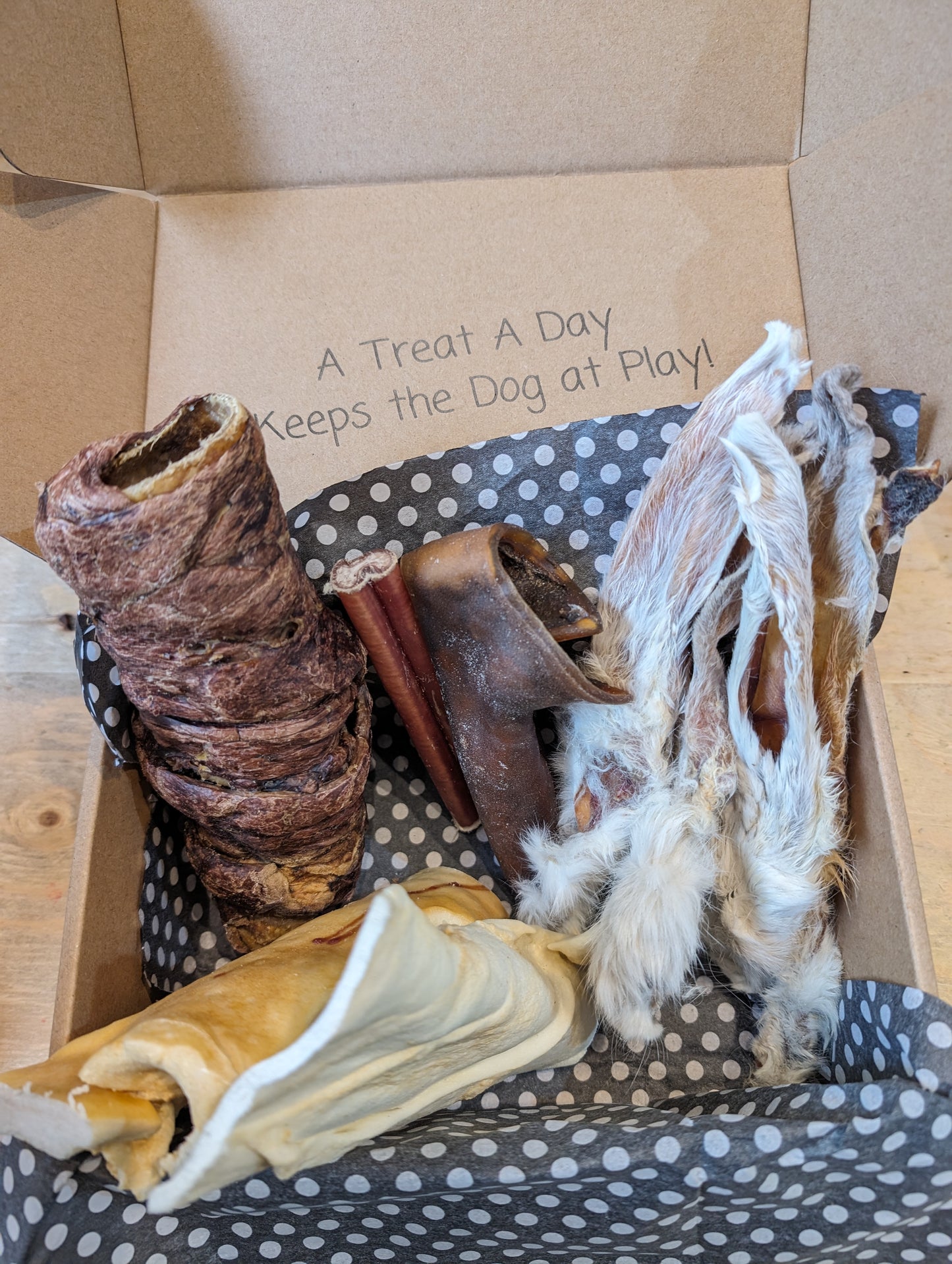 A variety of dog treats and chews inside an open box, all air dried. 