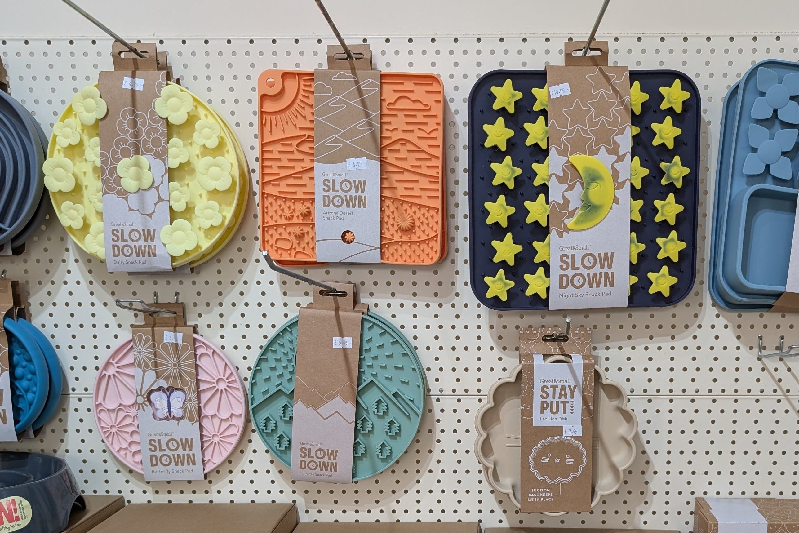 Display of pet bowls and accessories with  different designs and colours on a pegboard